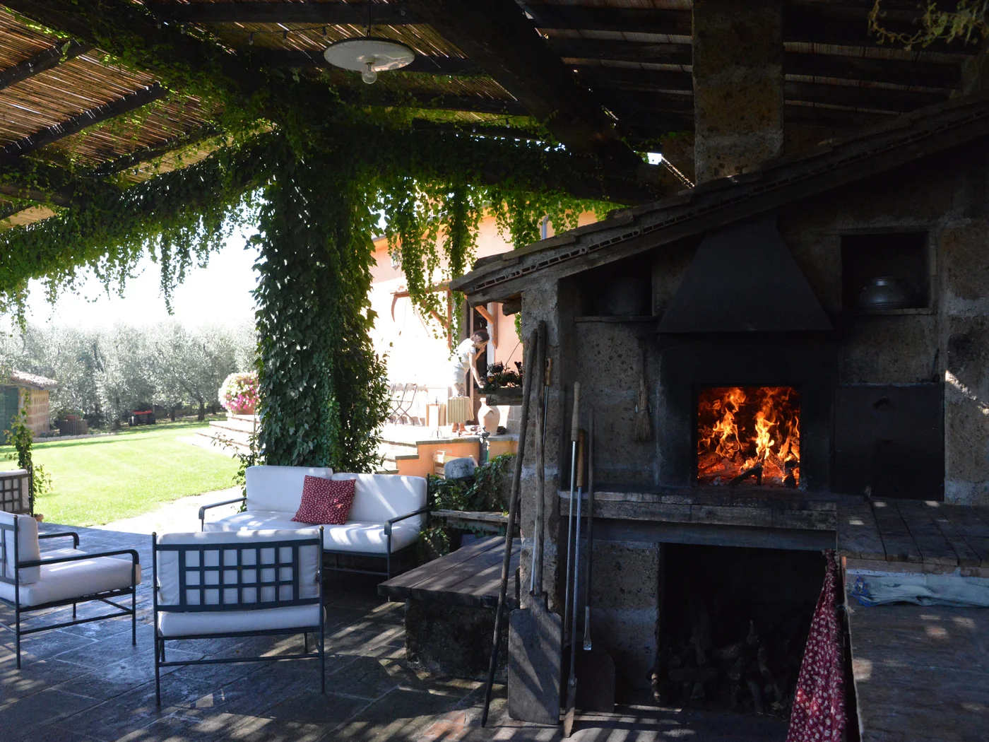 The back patio at Villa Eddarella in Soriano nel Cimino, Italy, with a fire burning in the 500-year-old wood-fired oven and olive trees beyond